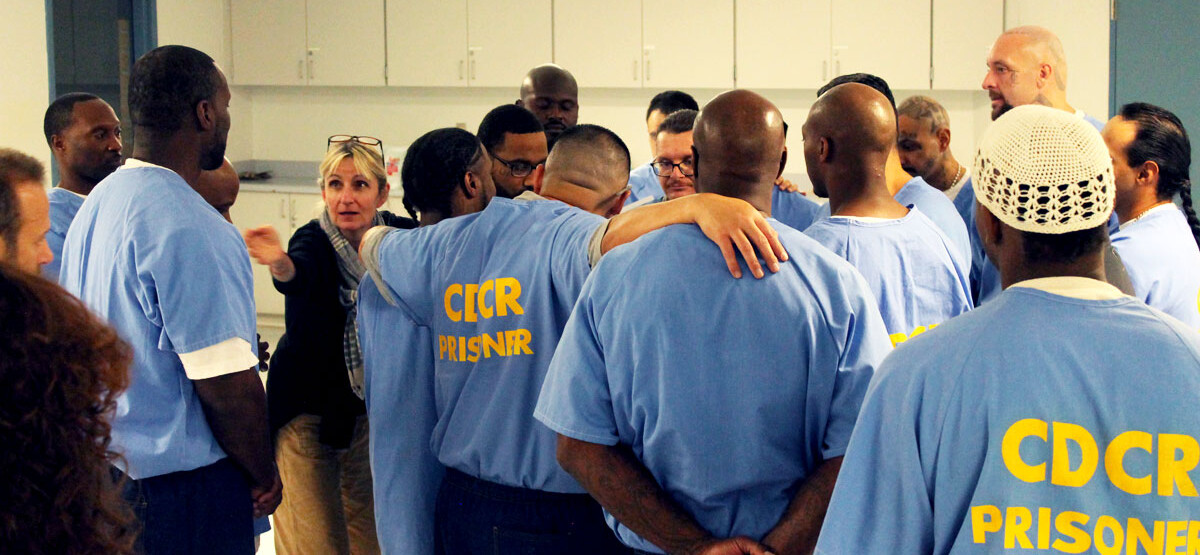 Group of men and Fritzi stepping inside the circle with arms around eachother